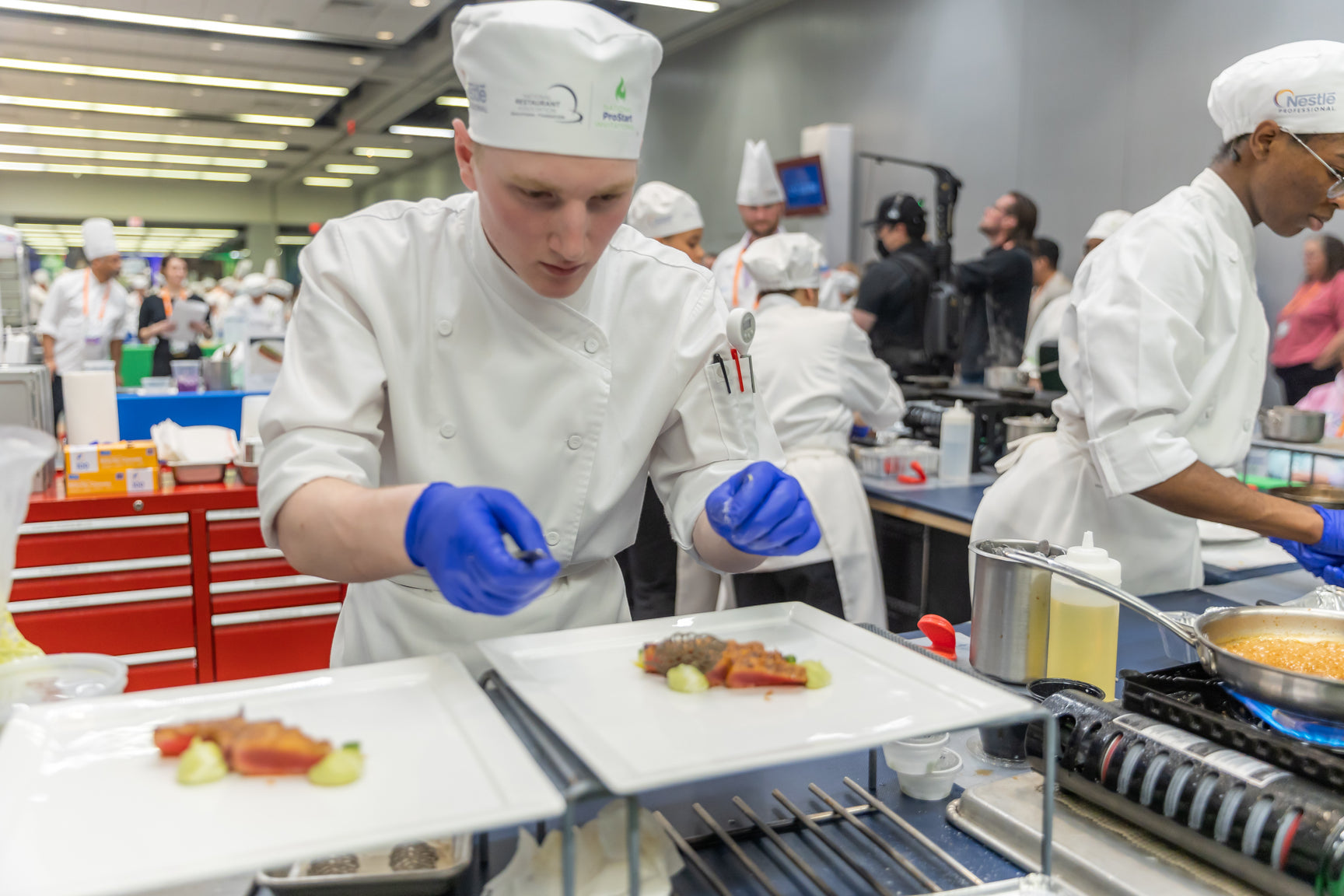 Culinary chefs plating and cooking in a kitchen with blue gloves on