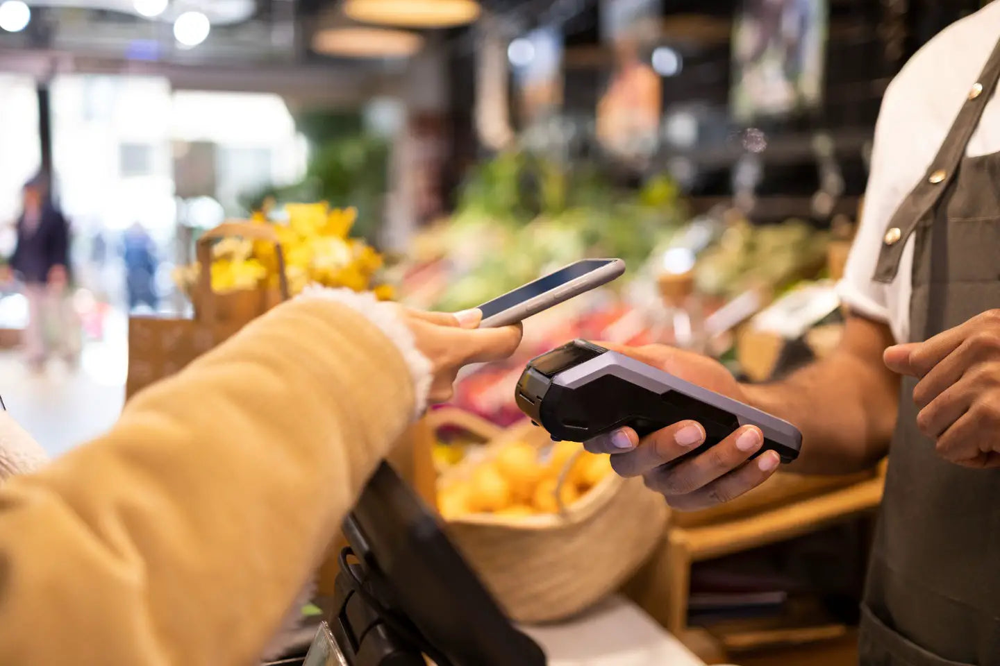 Transaction taking place as a customer uses their cell phone to complete a purchase with an employee at a grocery store